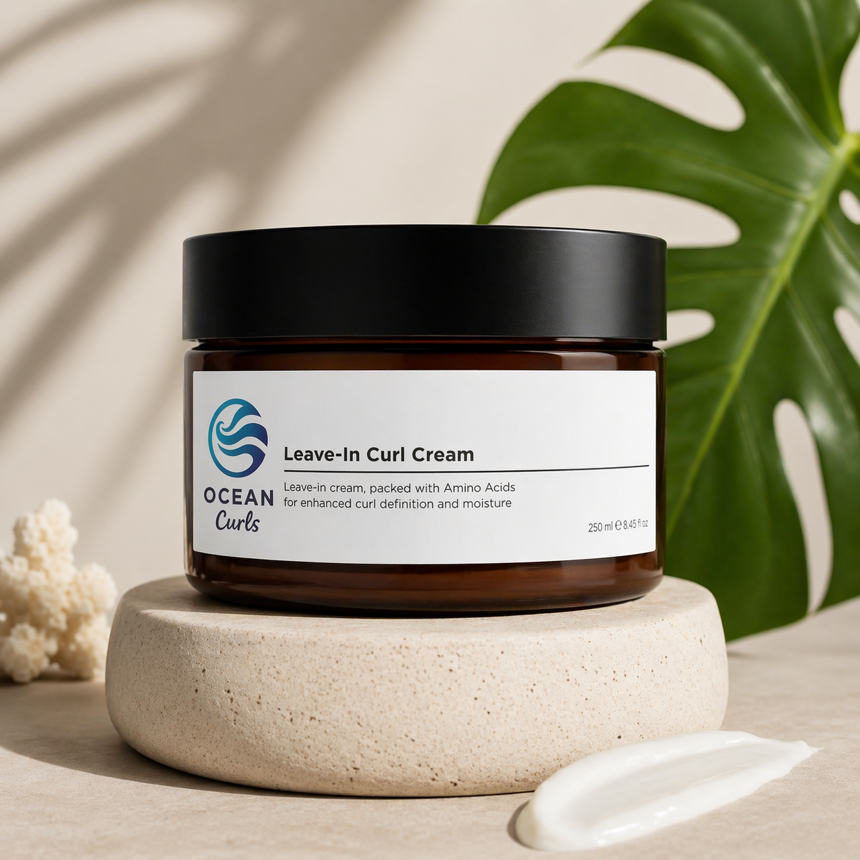 Black jar of Ocean Curls Leave-In Curl Cream resting on a round stone pedestal beside a monstera leaf